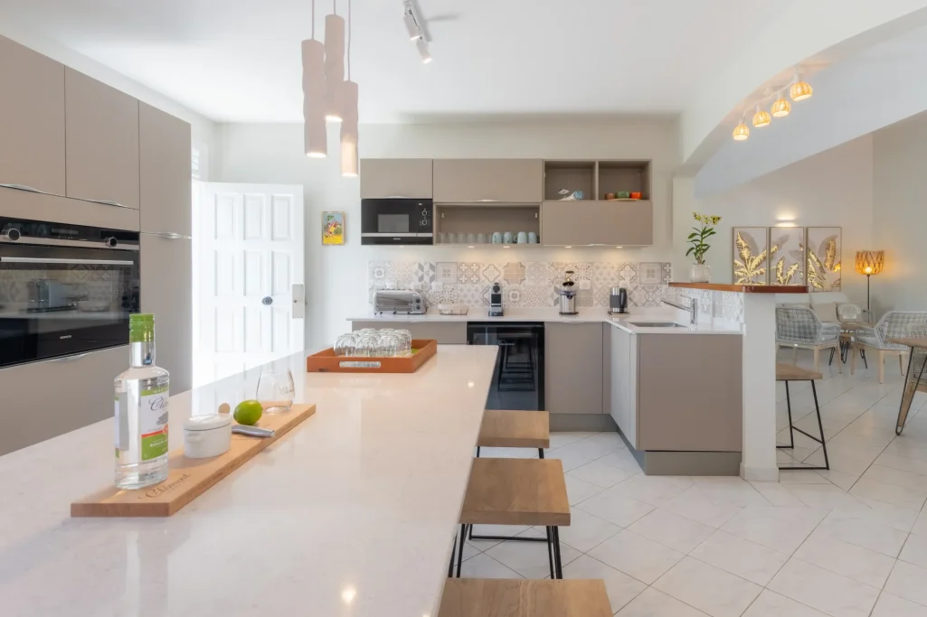 Une cuisine moderne avec un îlot central, des chaises en bois et un éclairage chaleureux.