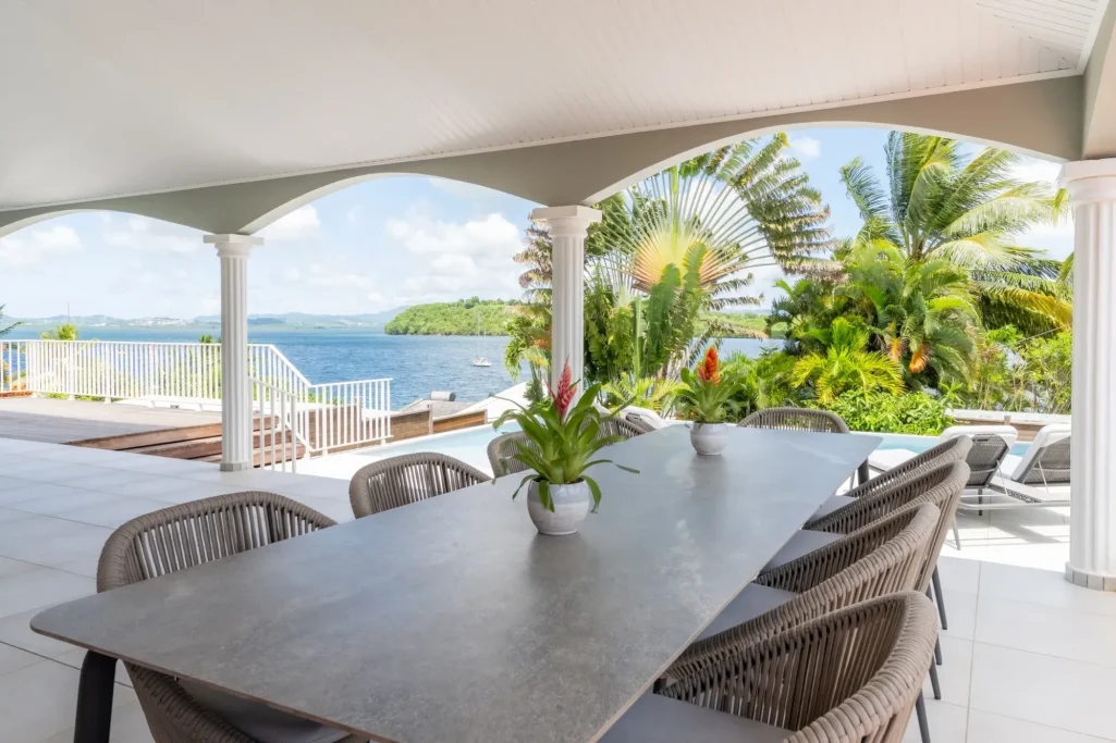 Table en extérieur avec vue sur la mer et des palmiers dans un cadre tropical.