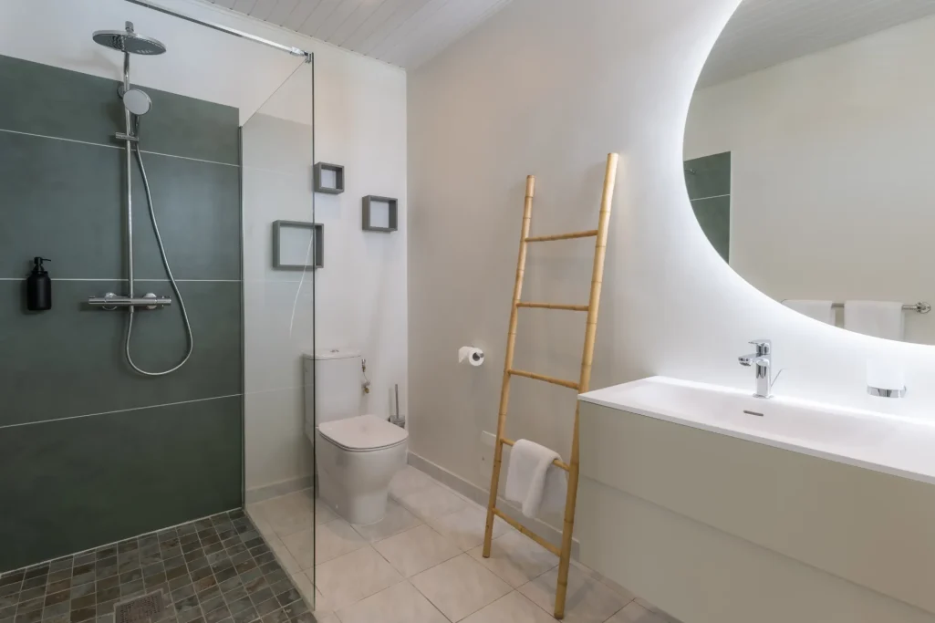 Salle de bains moderne avec douche, toilettes et lavabo sur un mur clair.