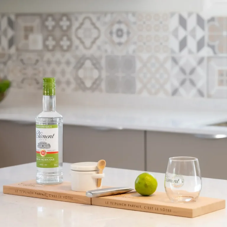 Bouteille de rhum, citron vert, verre et ustensiles sur une planche en bois. 
