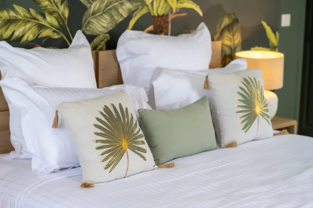 Couchage avec coussins décoratifs sur un lit, murs avec motifs de plantes.